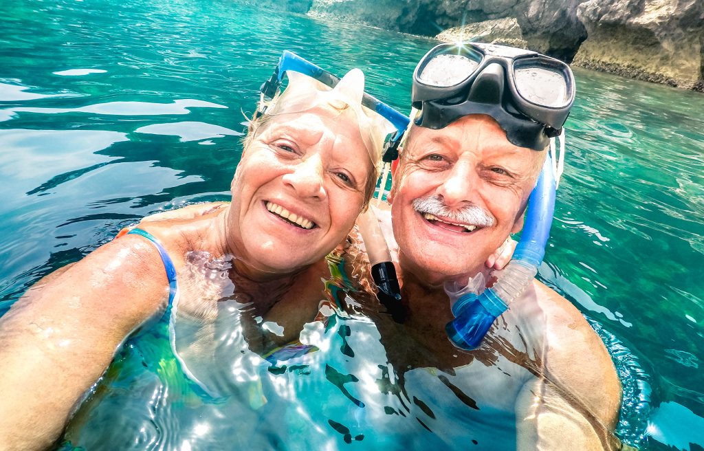 Older man and woman wearing scuba gear, in water.