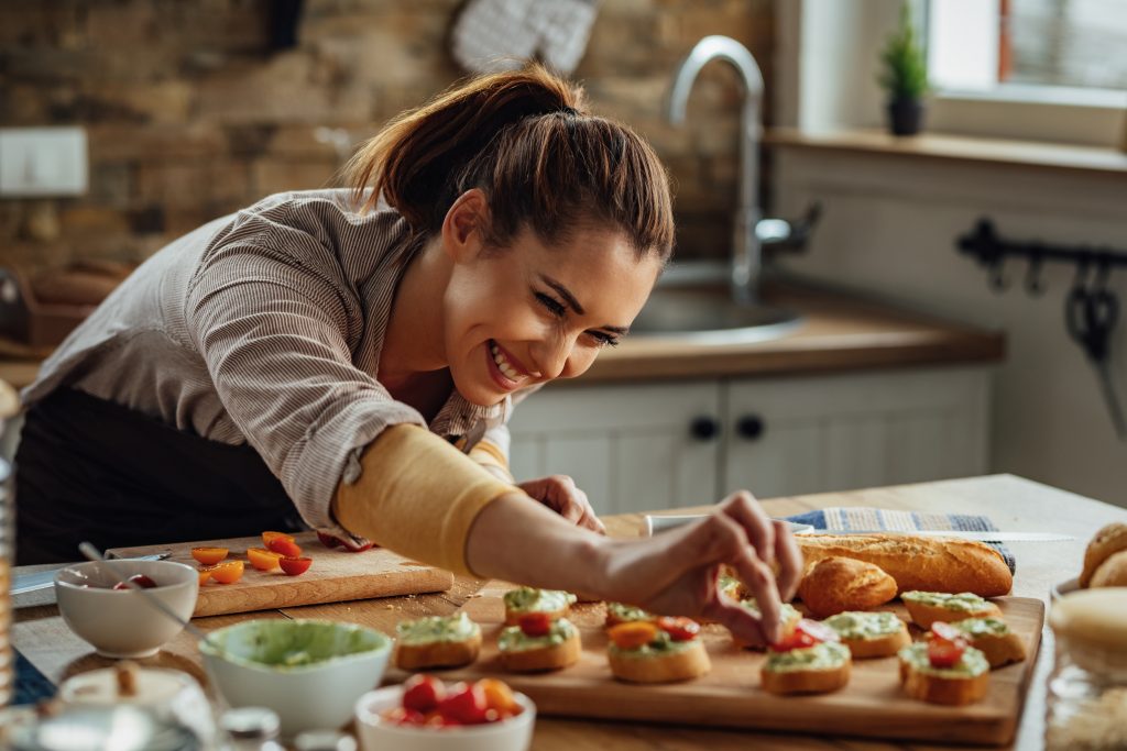 A happy cook leaning over food, putting on the finishing touches.