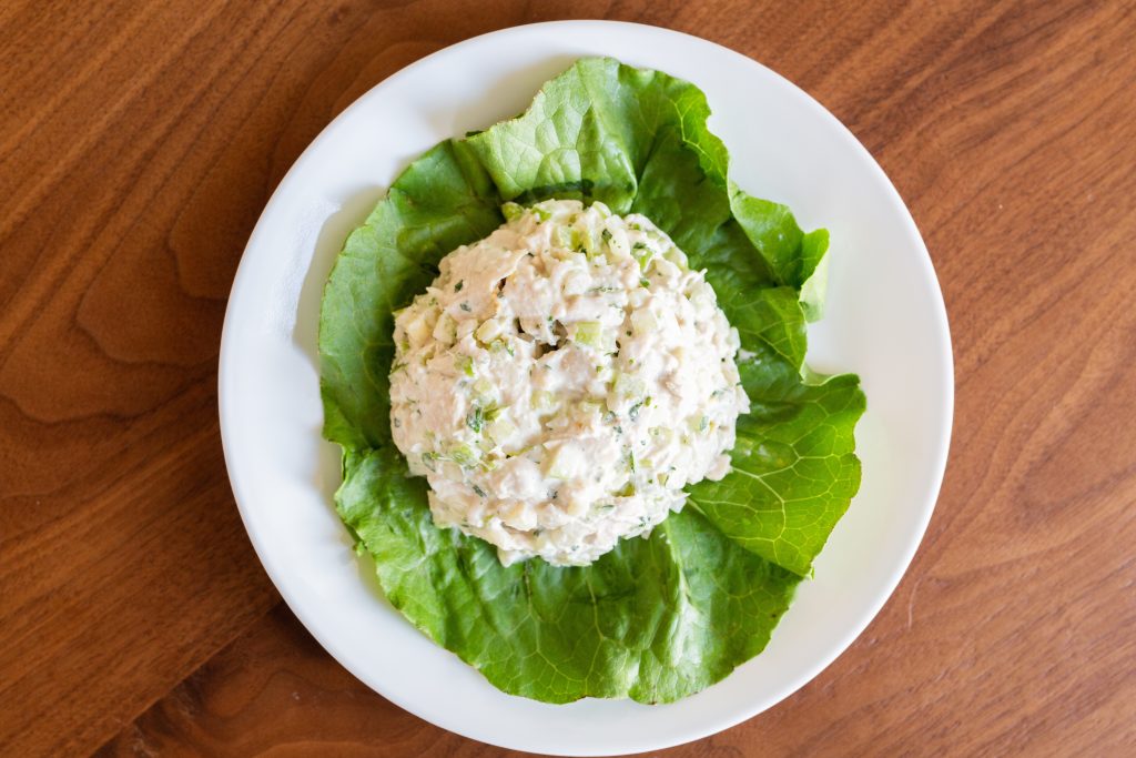 Chicken salad scoop on a bed of lettuce.