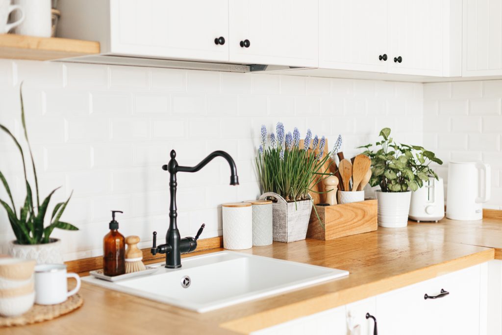 A cozy white kitchen decorated with a lot of green plants.