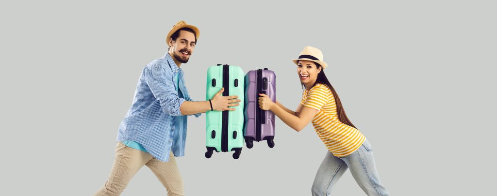 man and woman facing each other both holding suitcases.