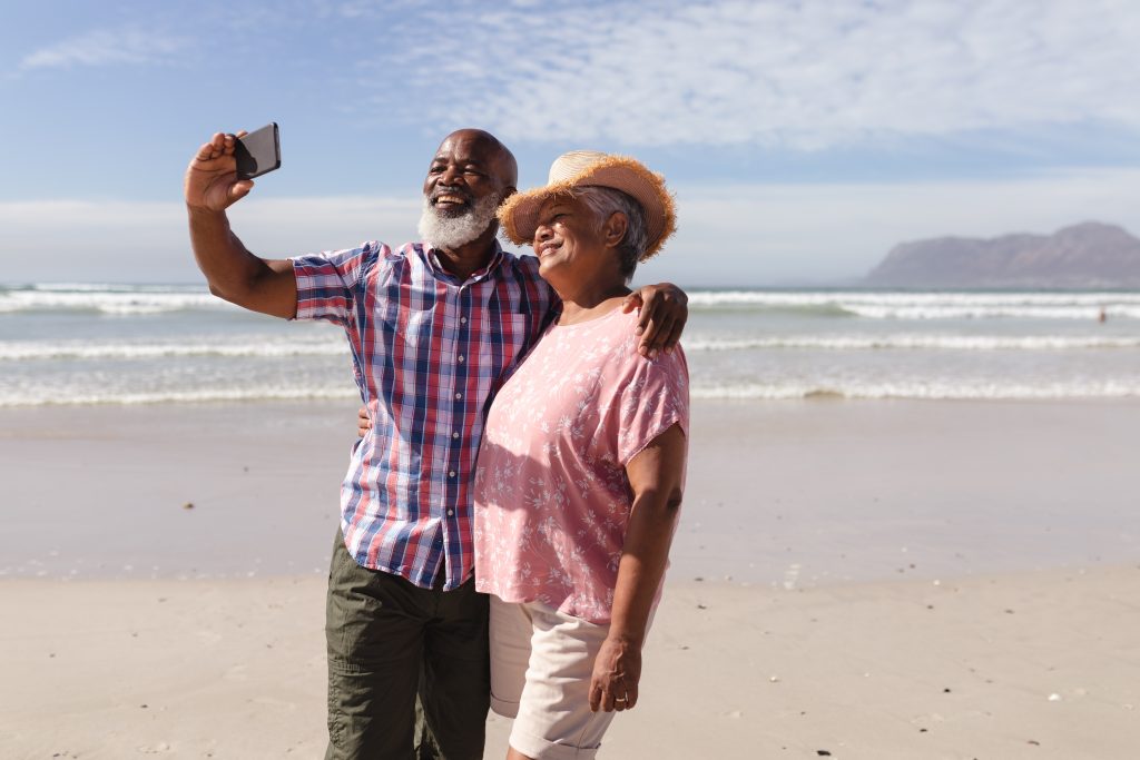 man and woman taking a selfie on the beach.