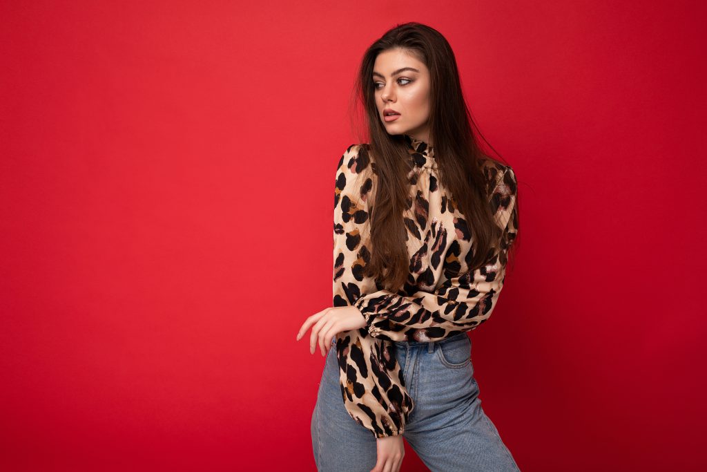 A woman wearing a leopard print blouse and jeans.