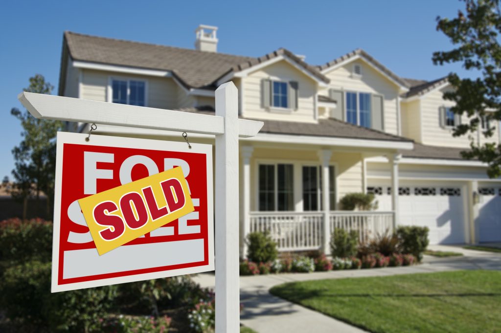 A large suburban home with a for sale, sold sign in the front yard.