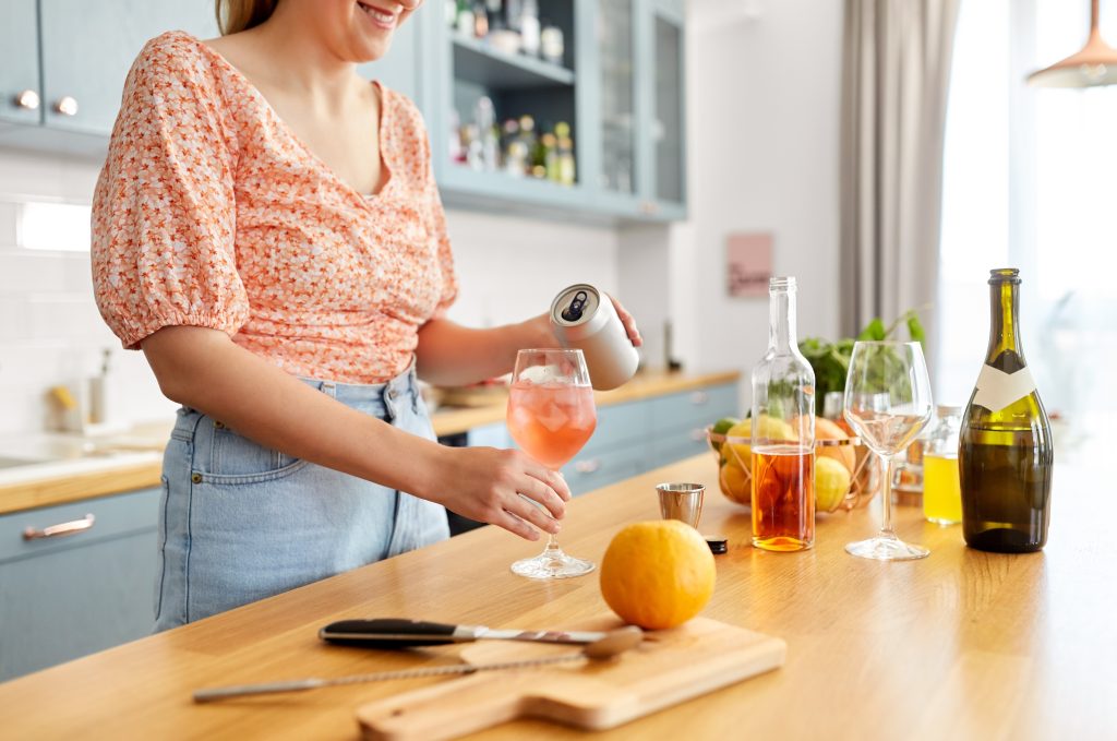 A woman in the kitchen mixing cocktails.