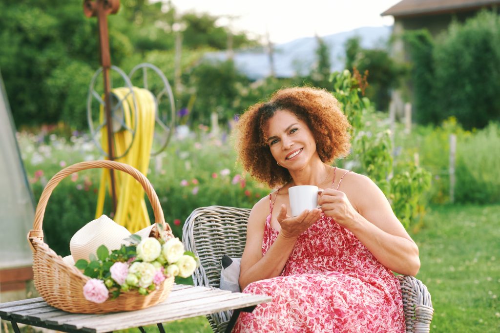 A woman sitting in a garden setting seeming content.