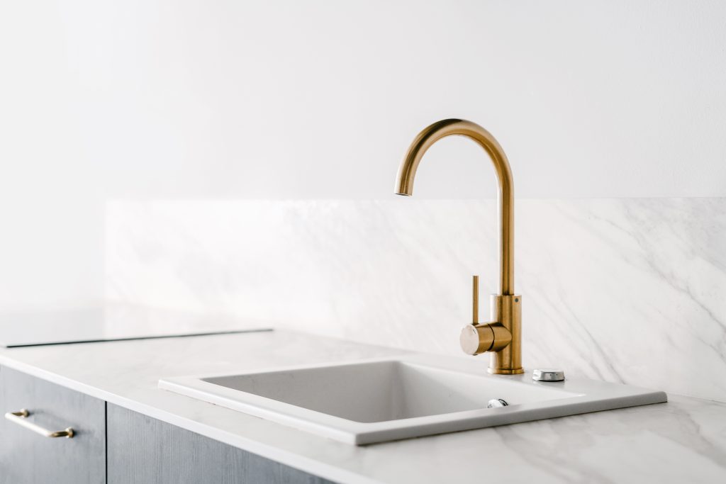White minimalist kitchen and gold faucet.