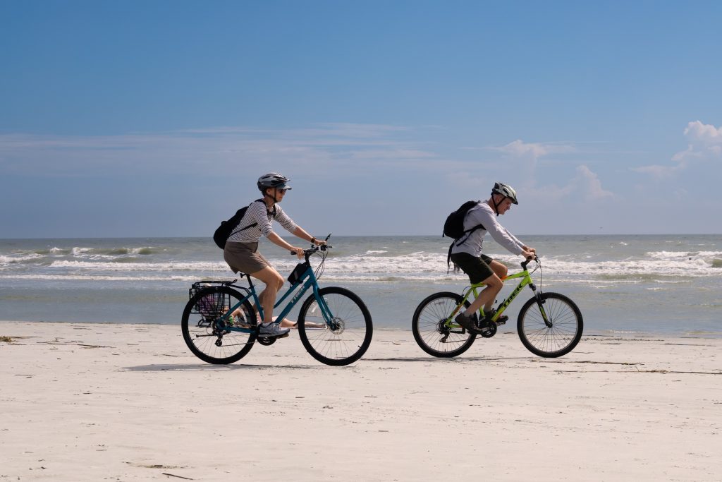 Two people on bicycles riding on the beach.