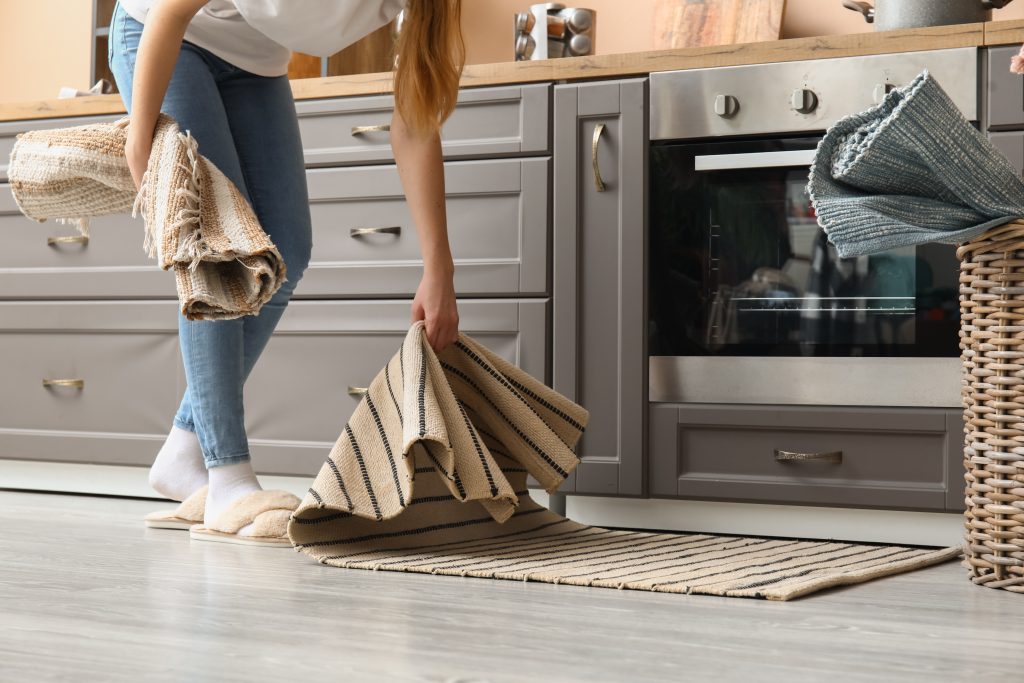 A person changing the kitchen rugs.