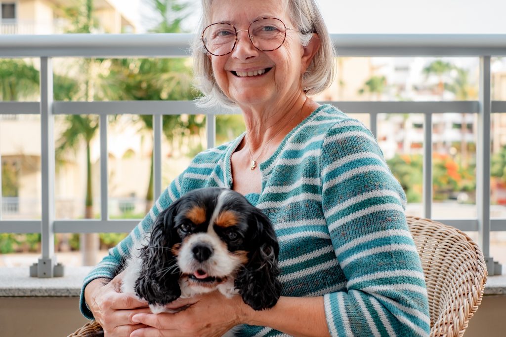 A senior woman holding a small white, black and brown puppy.