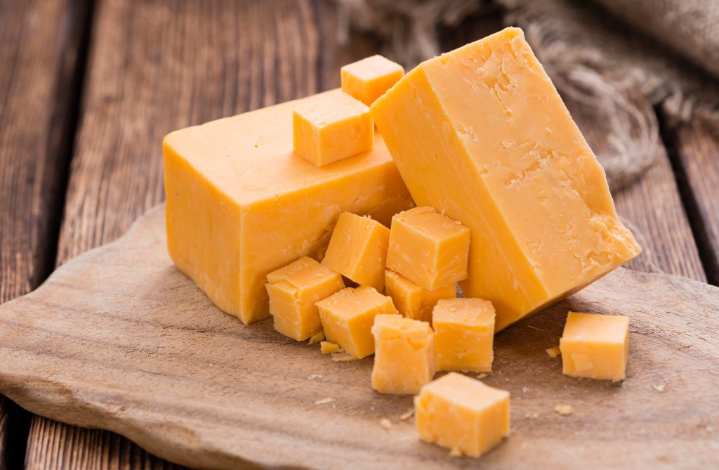 Cheddar cheese block with small chunks of cheddar around it.