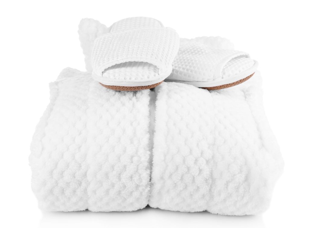 A white robe folded and slippers on top of it.