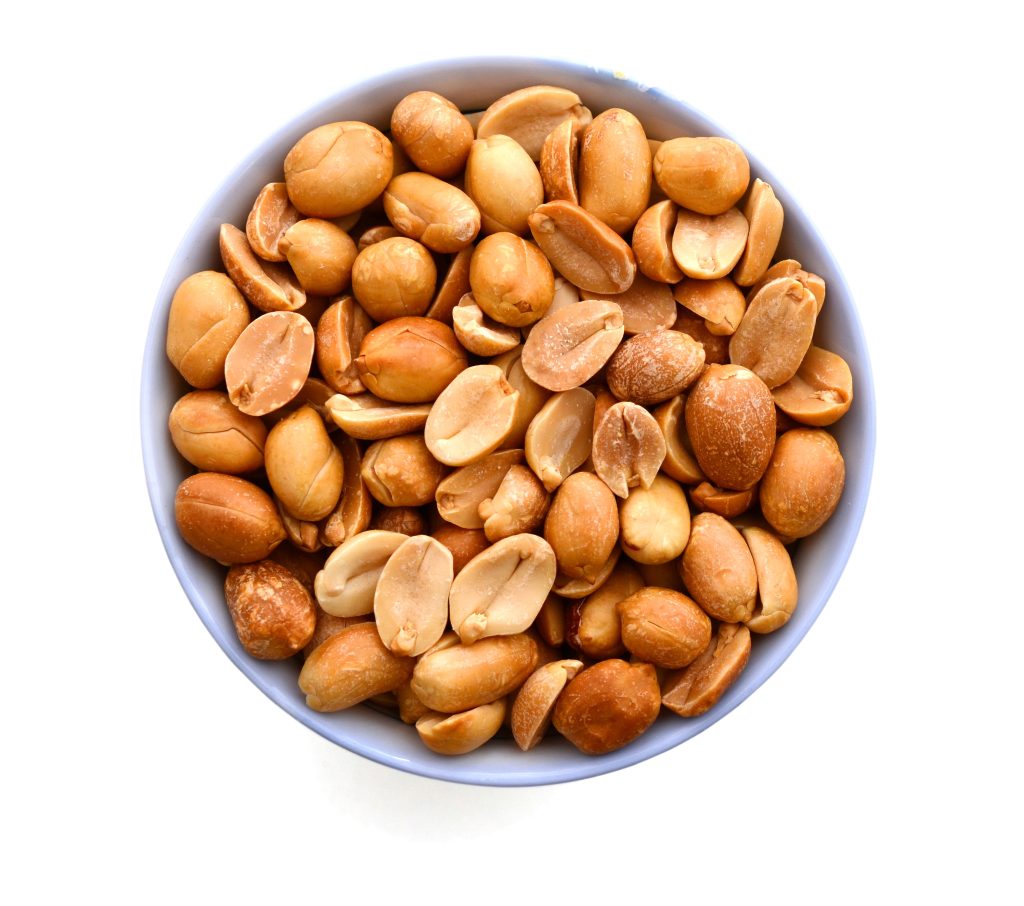 overhead view of a white bowl filled with shelled peanuts.