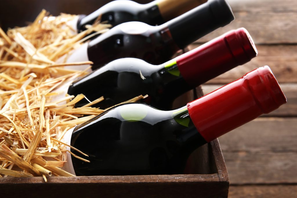 A wood box with filler and bottles of wine sticking out of it.