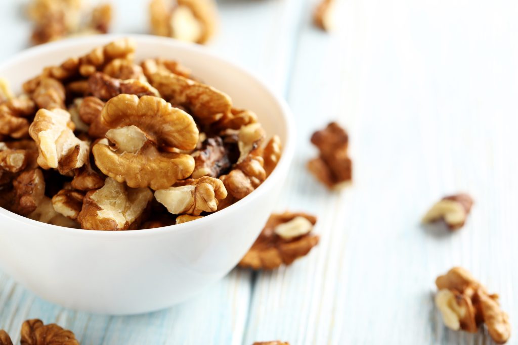 a white bowl with walnuts in it.