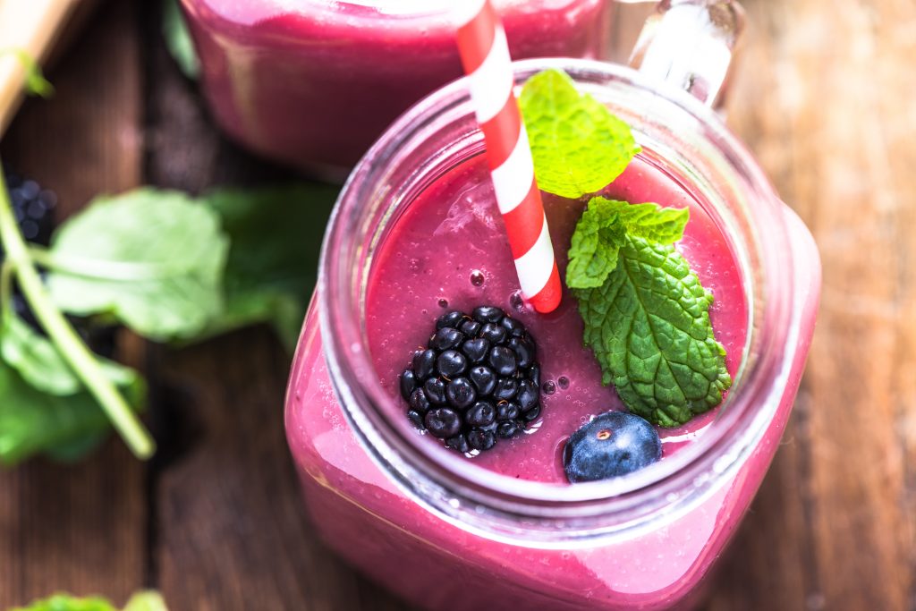 Overhead view of mixed berry smoothie in a clear glass, garnished with mint.