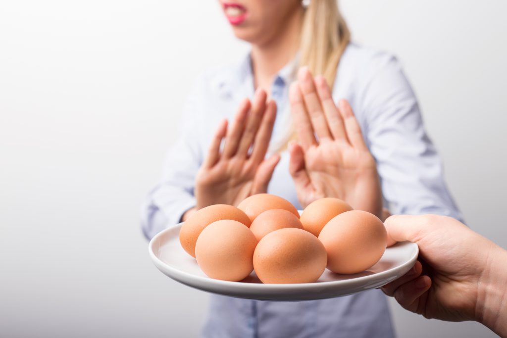 a woman with motioning stop with hands. a plate of eggs held in front of her.