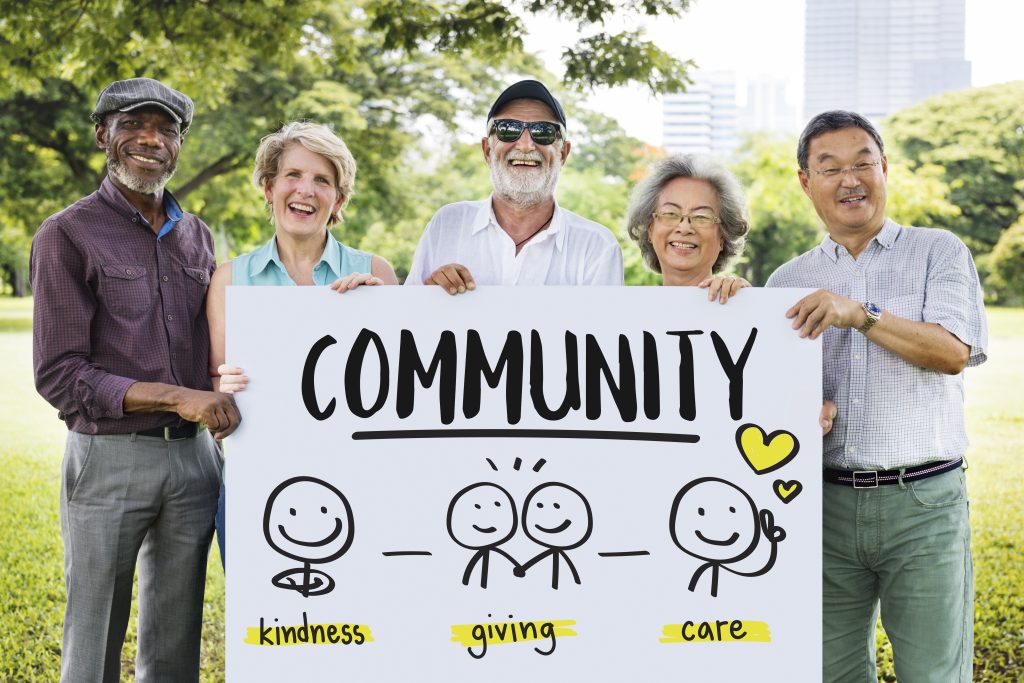 Old men and women holding a large sign that reads, Community.
