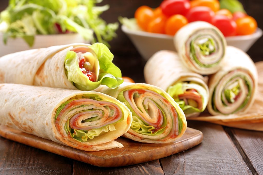 Tortilla sandwich wraps filled with meat and cheese, cut in half.