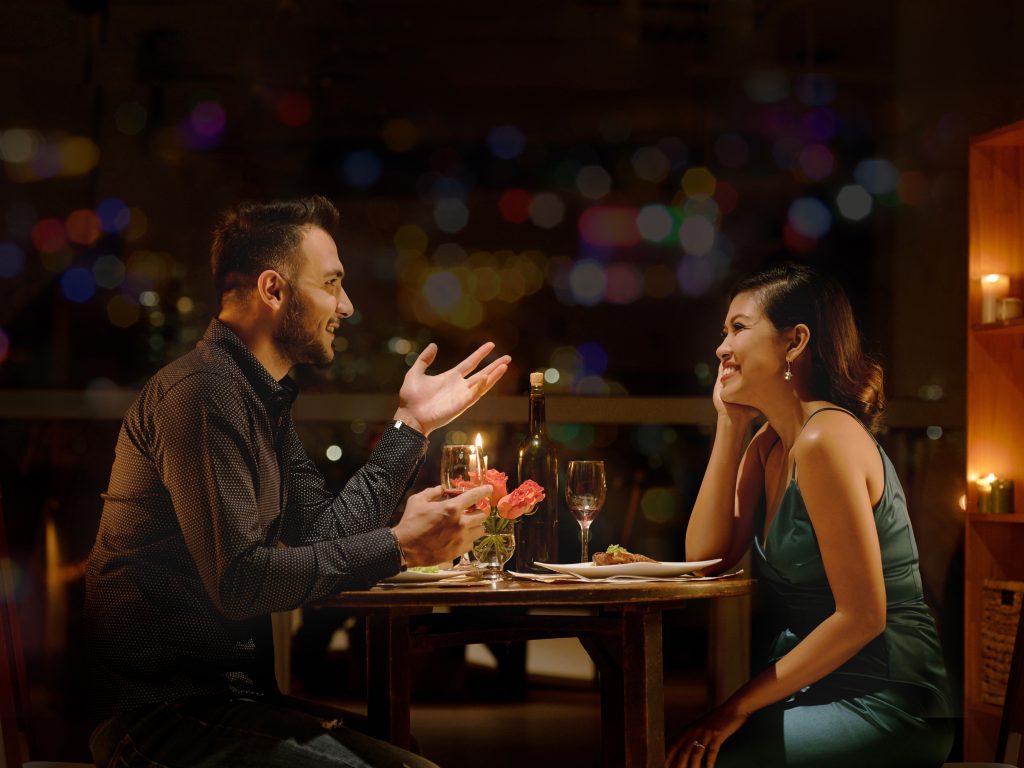 A man and woman on a date night at dinner, talking and laughing.