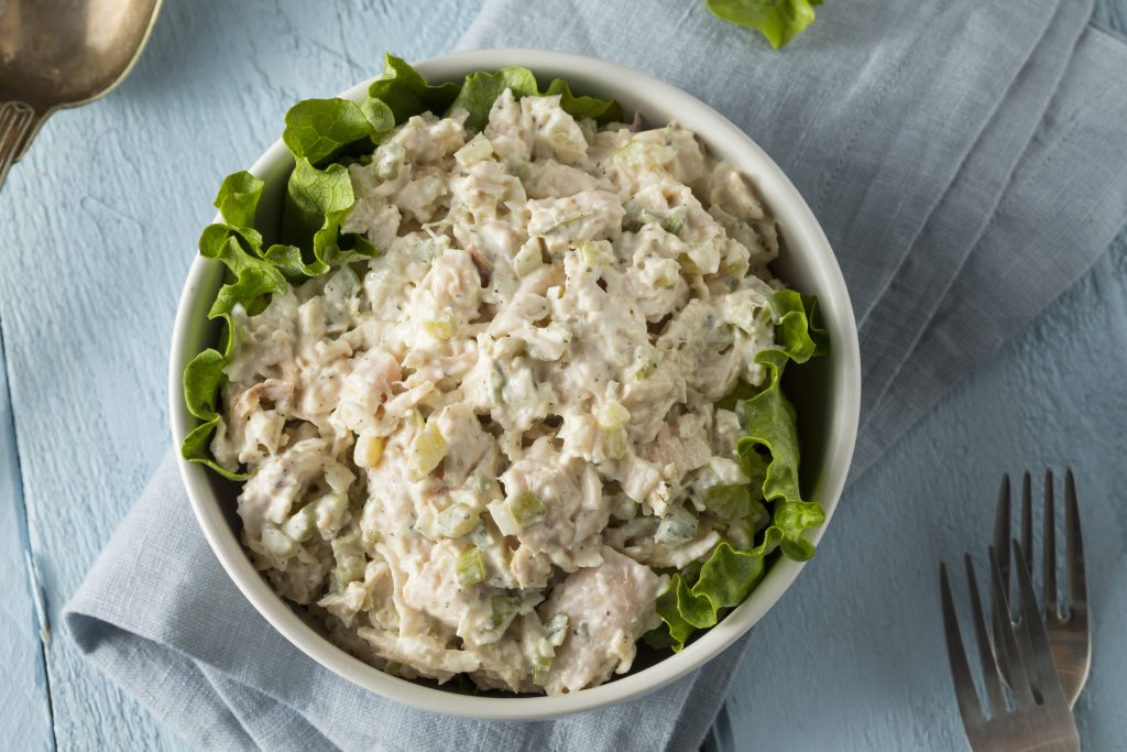 A lettuce-lined white bowl filled with chicken salad.