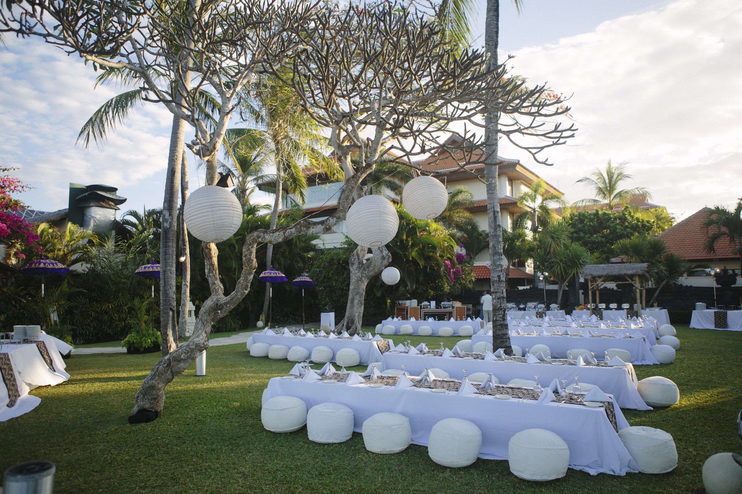 A themed outdoor dinner party decorated with white tables and seating.