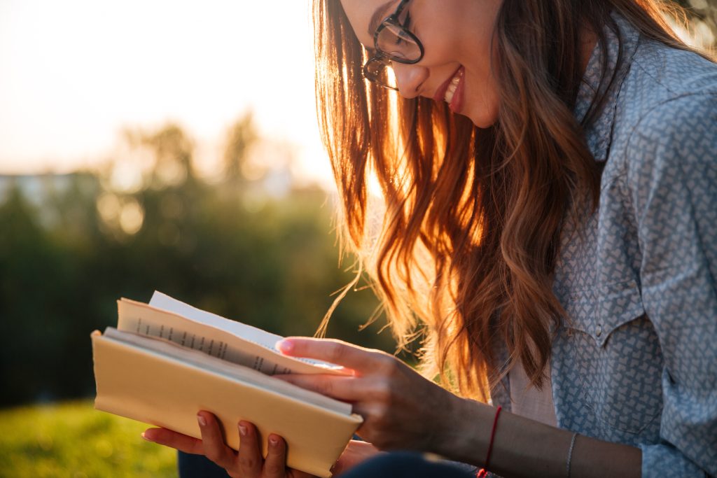 A woman sitting outside reading a book.