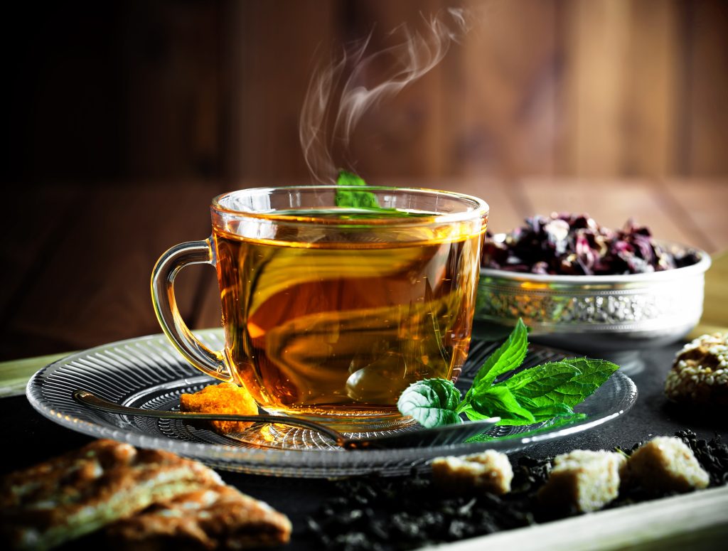 A clear cup of hot tea with steam rising from it.