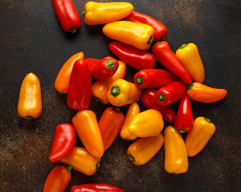 a large pile of orange and red mini sweet peppers.