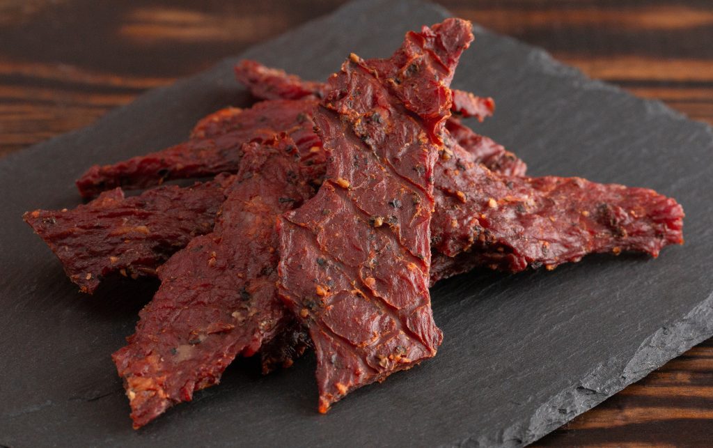 a pile of beef jerky on a black stone slab.