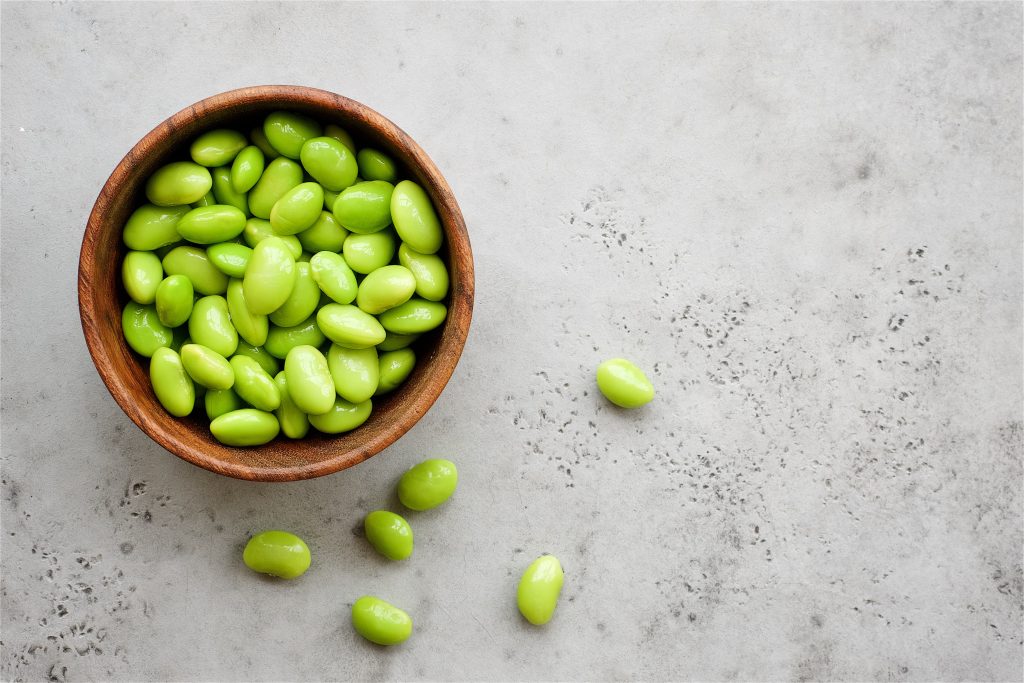 a wooden bowl of edamame. 