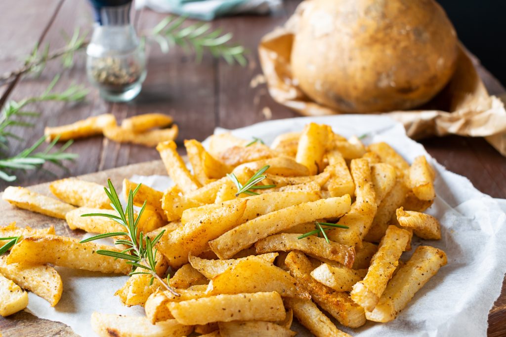 Jicama fries on a white plate, whole jicama in the background.