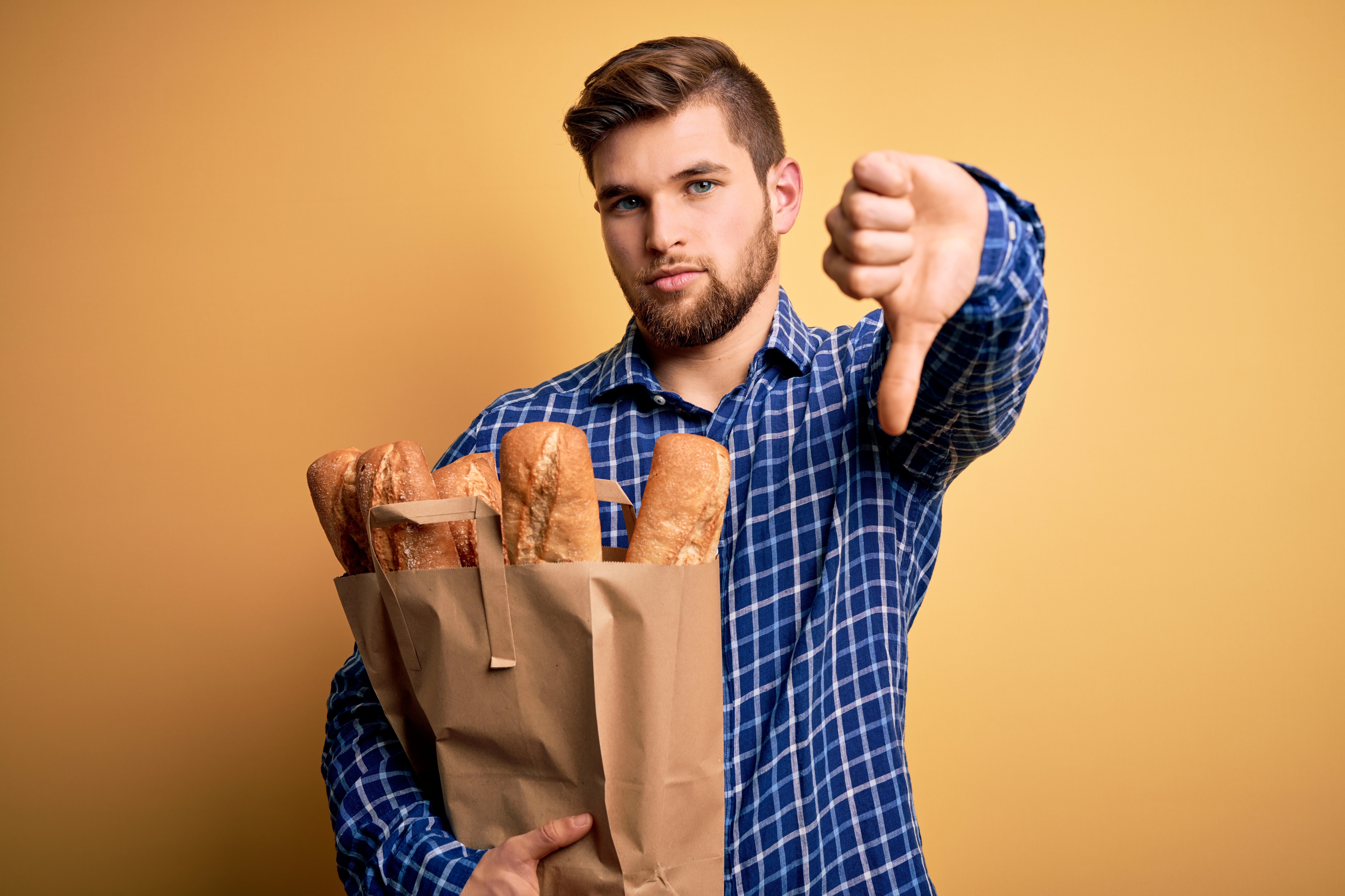 a man holding a bag of bread giving thumbs down.