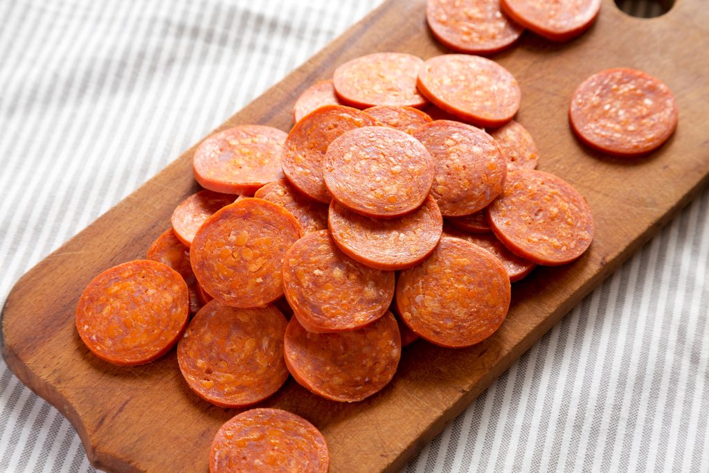 pepperoni slices on a wood board.