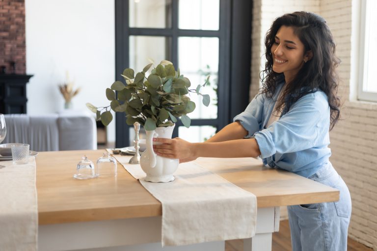 A woman decorating the table with flowers.