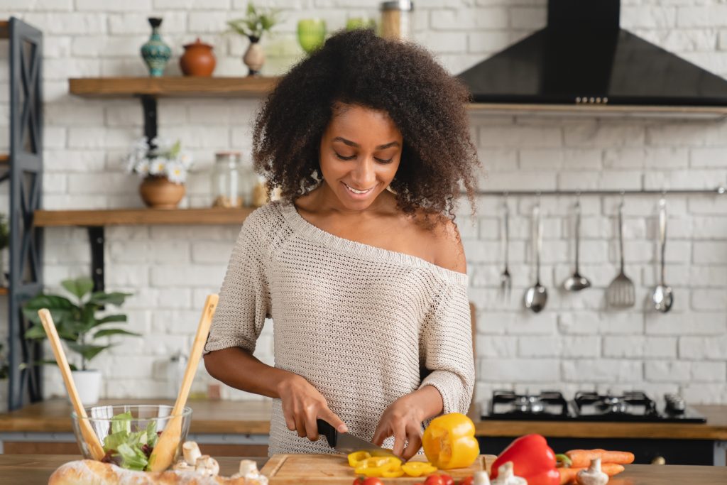 A woman cutting vegetables at the kitchen counter.