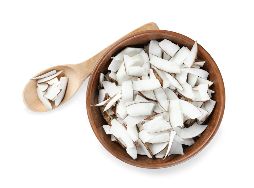 a wooden bowl filled with flaked coconut pieces.