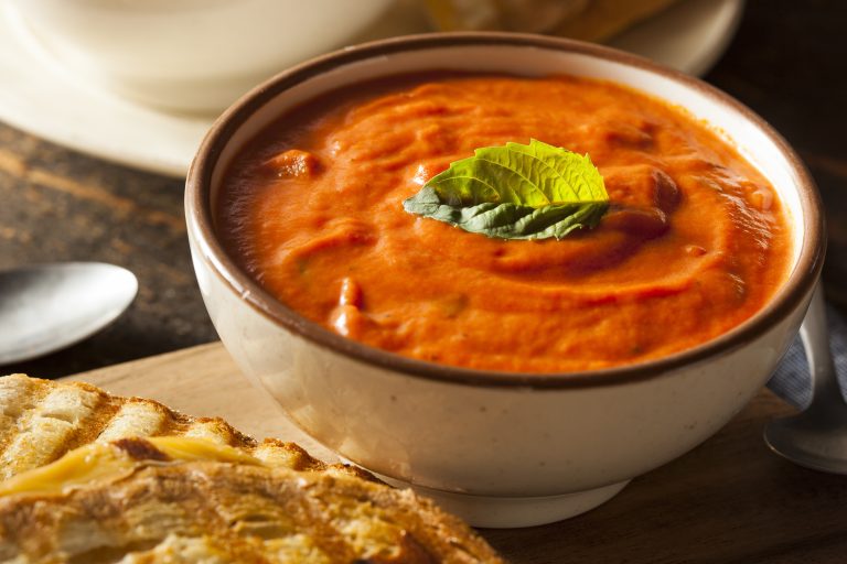 Creamy tomato soup in a natural bowl with a side of bread.