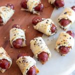 pigs in a blanket on a wood and white marble cutting board.