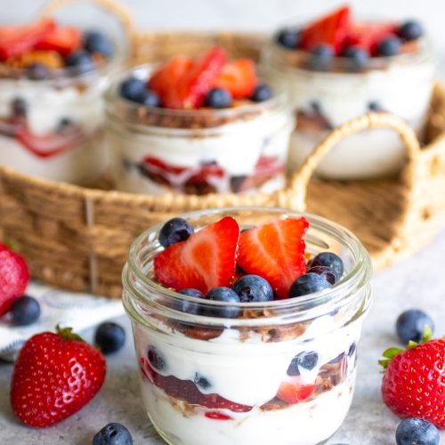 yogurt berry granola parfaits in glass jars.