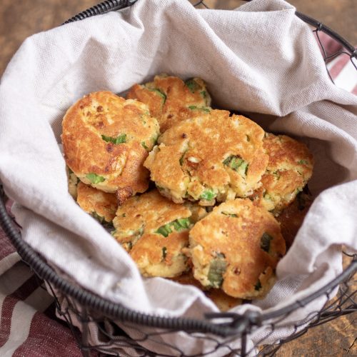 Fried okra fritters in a metal basket lined with a tan linen napkin.