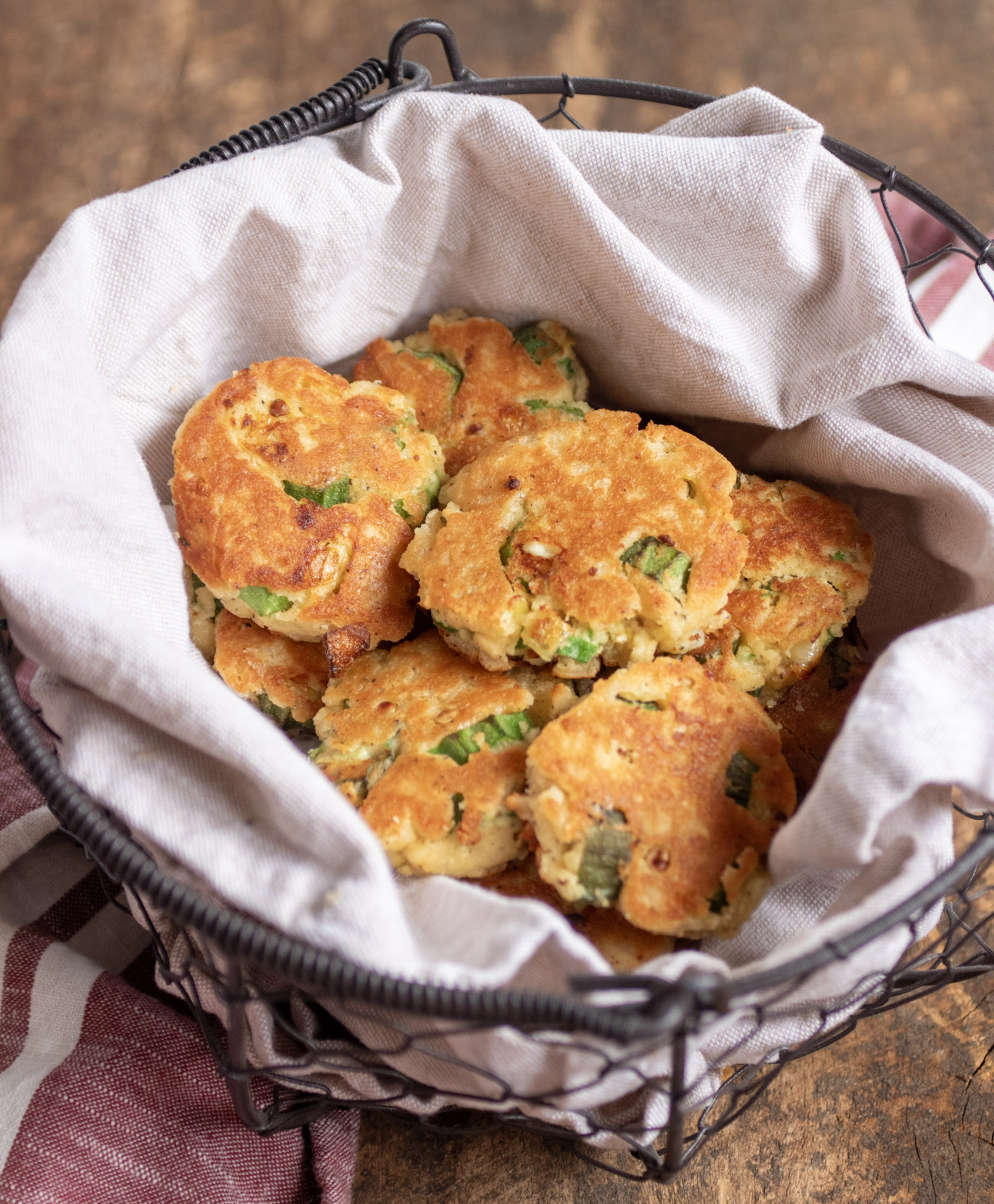 Fried okra fritters in a metal basket lined with a tan linen napkin.